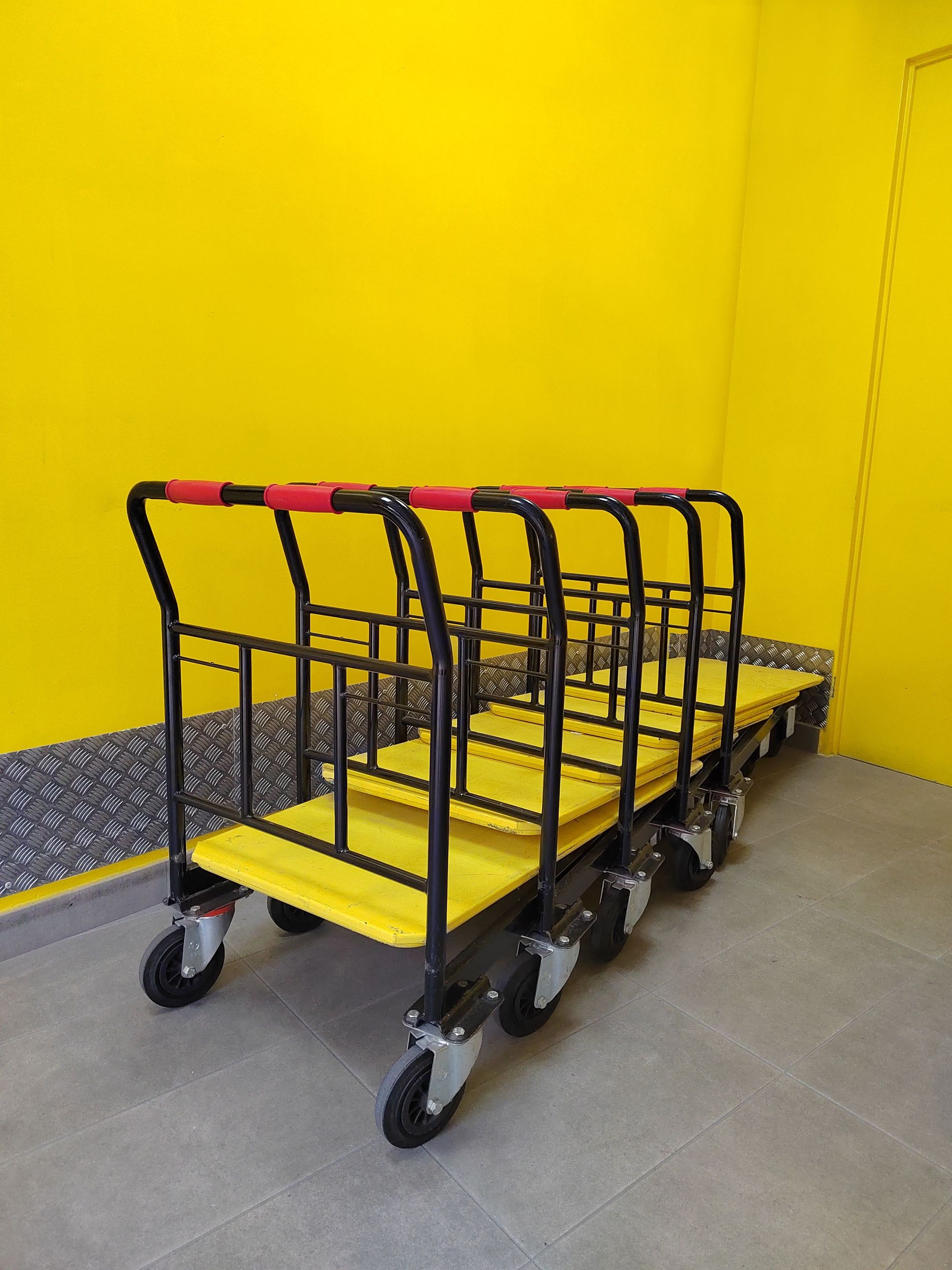 Multiple industrial dollies lined up in a vibrant yellow room.